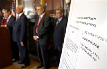An poster with an enlarged view of the dismissal of the 2001 Los Angeles Police Department consent decree, ending federal oversight of the department prompted by the Rampart corruption scandal, is seen as the mayor, police chief, and police commission board members appear at police headquarters, Thursday, May 16, 2013, in Los Angeles. (AP Photo/Reed Saxon).