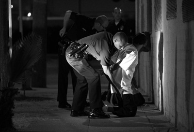 Officer Clay Bell pats down a suspected gang member while on patrol in the Newton Division. (Brian van der Brug)