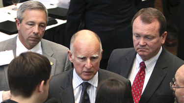 Gov. Jerry Brown talks with reporters after speaking at the Alliance of California Law Enforcement's legislative day in Sacramento. With the governor are Merced County Sheriff Mark Pazin, left, and Long Beach Chief of Police Jim McDonnell. (Rich Pedroncelli, Associated Press / April 6, 2011)