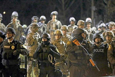 Police and Missouri National Guardsmen stand guard as protesters gather in front of Ferguson Police Department on Friday, Nov. 28, 2014, in Ferguson, Mo. Several protesters have been taken into custody during a demonstration outside the police department. Tensions escalated late Friday during an initially calm demonstration after police said protesters were illegally blocking West Florissant Avenue. <i>(AP Photo/Jeff Roberson)</i>