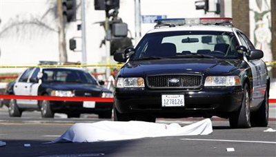 A body is covered by a blanket after a shooting with police in Hollywood, California December 9, 2011. Credit: Reuters/Mario Anzuoni