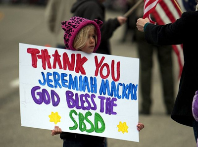 Allison Seratt, 5, holds a sign along the funeral route for San Bernardino County Sheriff's Deputy Jeremiah MacKay, who was killed in a gunfight with Christopher Dorner. Seratt's father is a sheriff at the Yucaipa station where MacKay also worked. (Gina Ferazzi / Los Angeles Times / February 21, 2013)