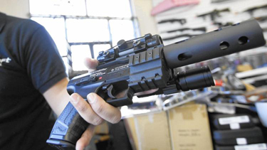 Jordan Baylon holds a realistic-looking air gun. For him and many others in the world of airsoft fighting, the appeal of their weapons lies in their realism. (Bob Chamberlin / Los Angeles Times)
